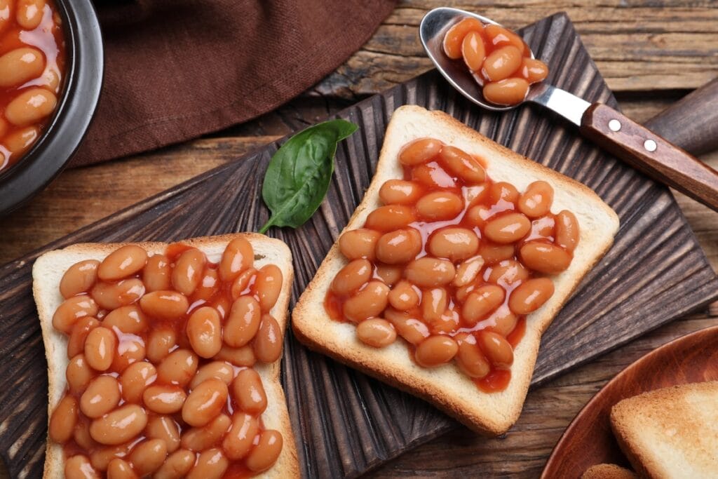 Toasts with beans on wooden table.