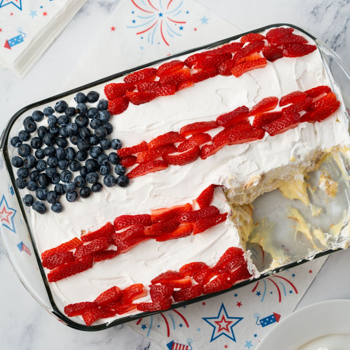 Flag icebox cake filled with banana pudding and Nila wafers on a marble background with 4th of July napkins.