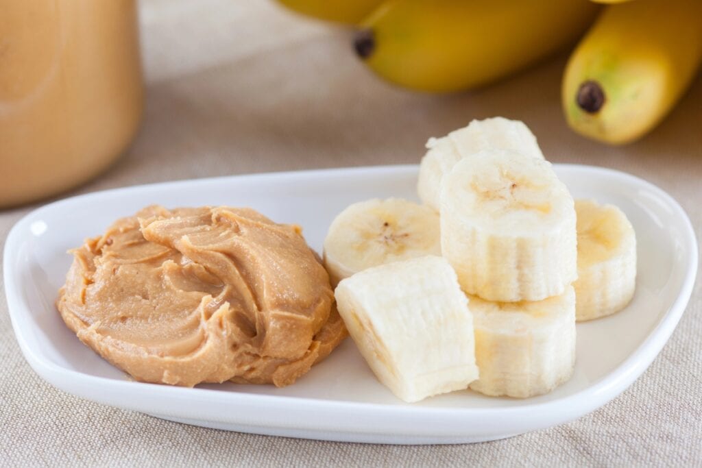 Banana and peanut butter on a white plate.