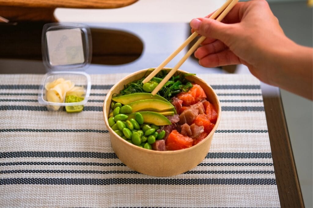 Ready-to-eat meal with salmon, avocado, rice, seaweed salad, and edamame.
