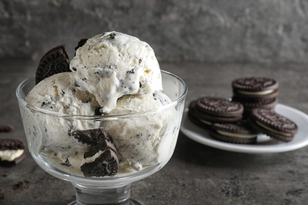 A serving of cookies and cream ice cream in a clear glass.