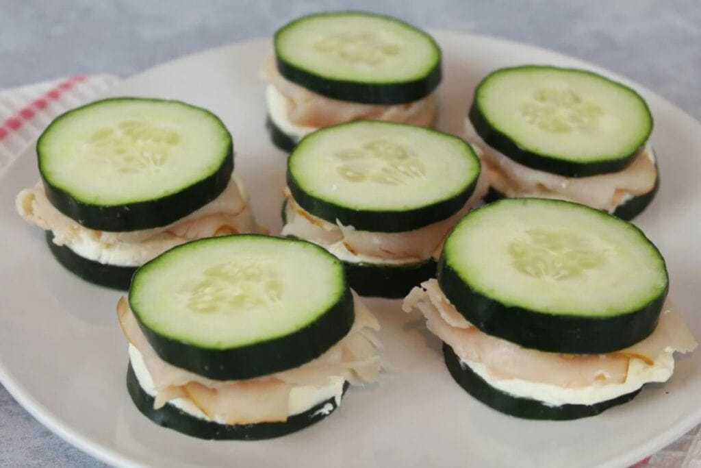 Mini cucumber sandwiches on white plate.