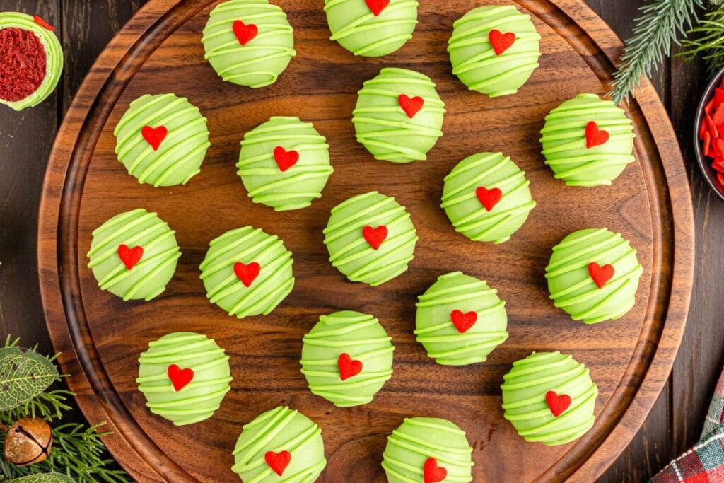 Grinch Oreo balls on a wooden board.