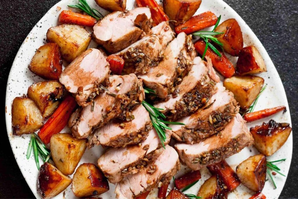 Slices of pork tenderloin with potatoes on a plate.