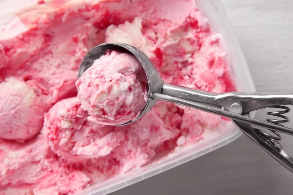 Strawberry ice cream with a metal scoop.