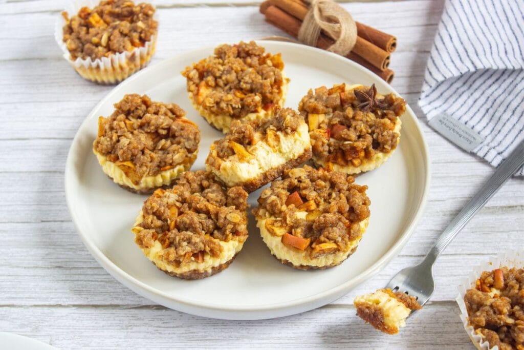 Mini apple crisp cheesecakes on a round plate.