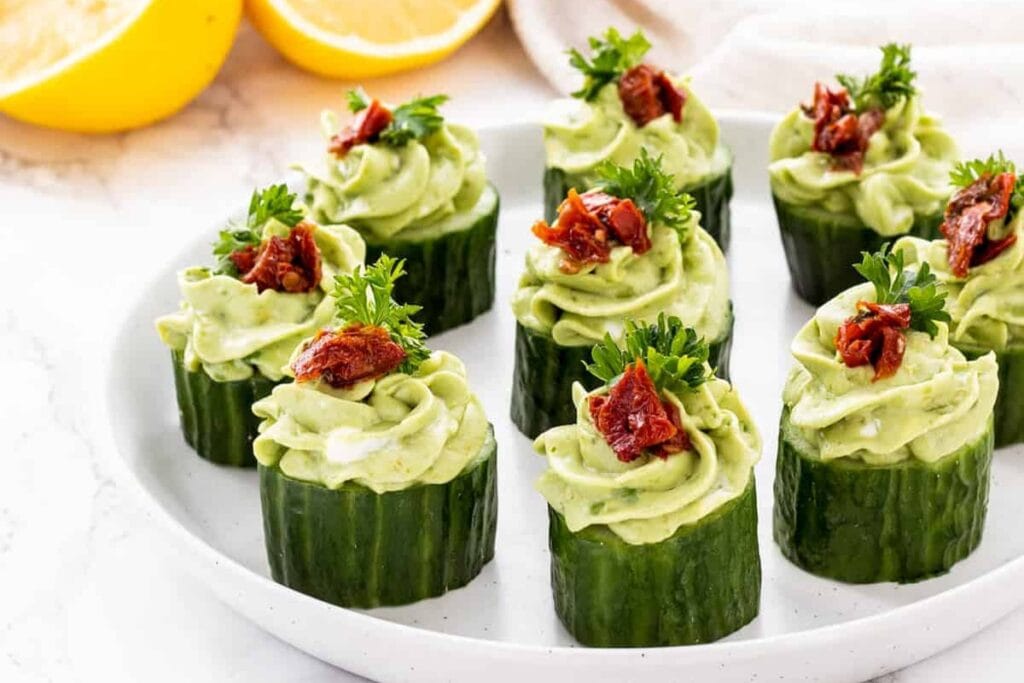 Avocado goat cheese cucumber bites on a white plate.