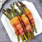Close-up of bacon-wrapped asparagus on a white plate.