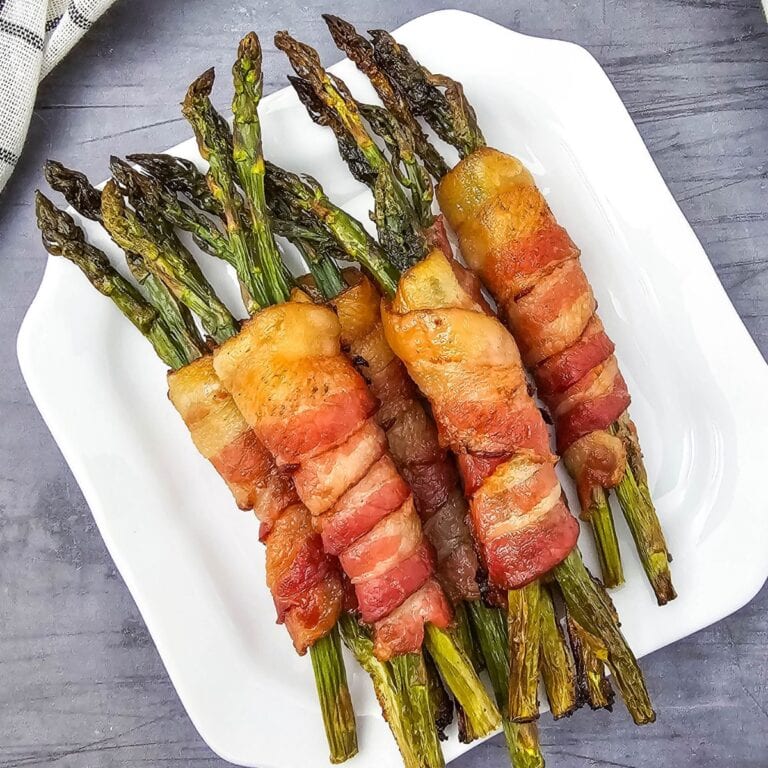 Close-up of bacon-wrapped asparagus on a white plate.
