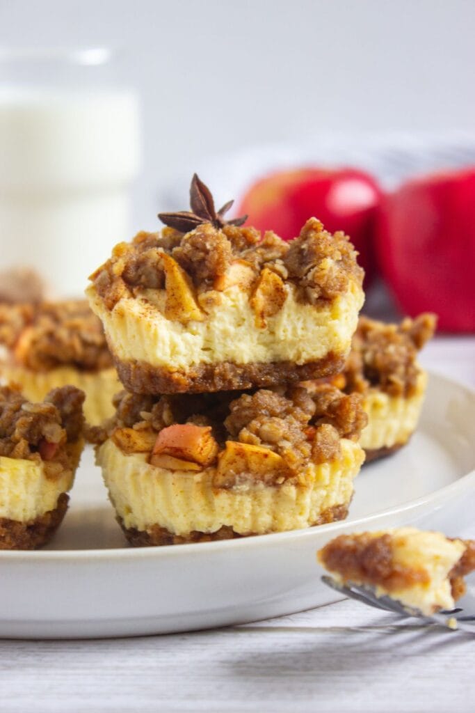 Mini apple crisp cheesecakes on a round plate.