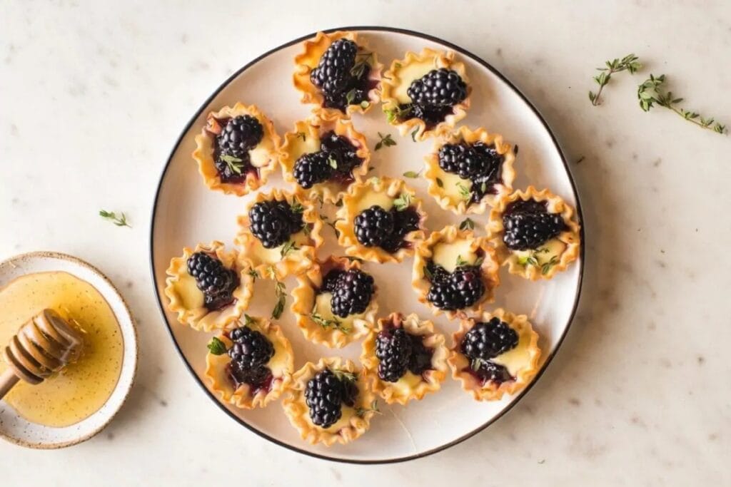Brie phyllo cups with blackberry and thyme on a plate.