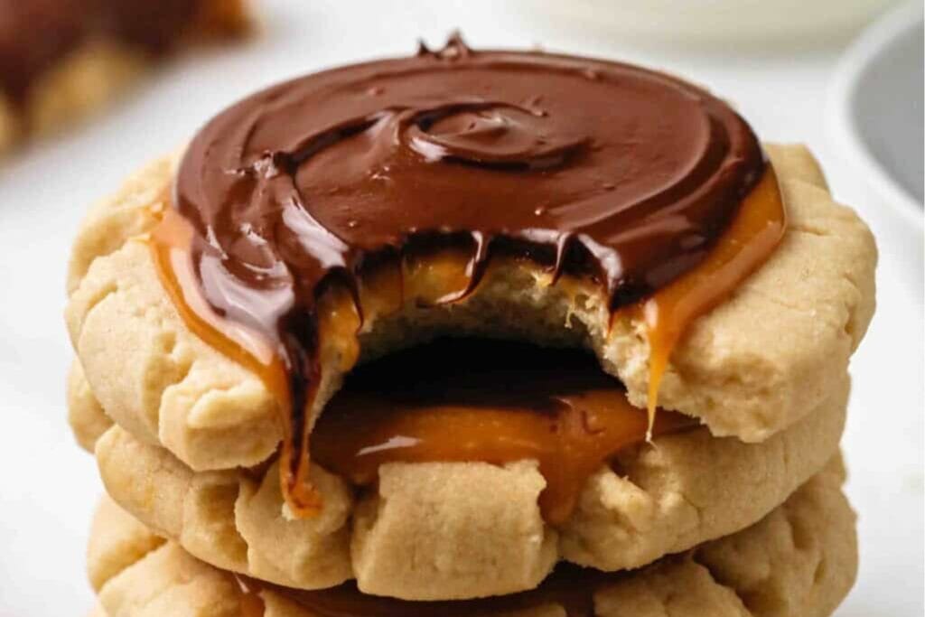 Three stacked Chilled Crumbl Twix Cookies topped with caramel and chocolate.