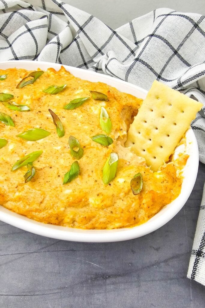 Hot crab dip served in a rectangular dish with crackers on the side.