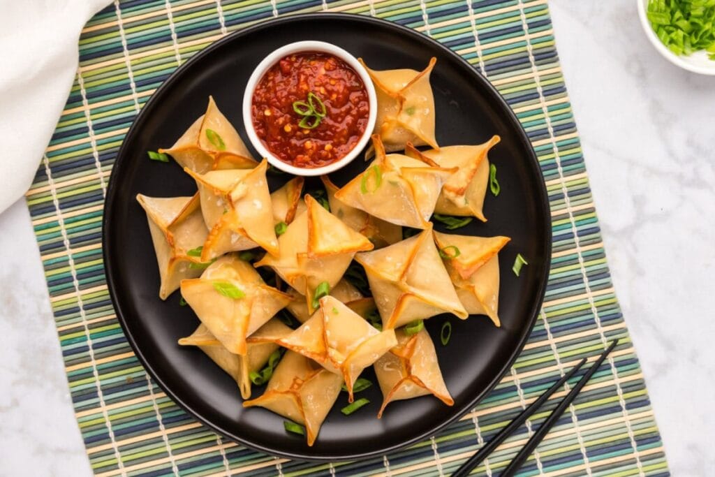 Crab Rangoon on a black plate.