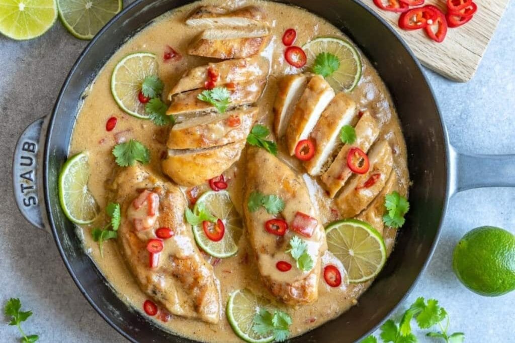 Creamy coconut chicken with chili, lime, and cilantro in a skillet.