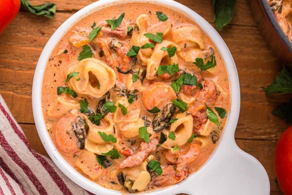 Creamy tortellini soup in a white soup cup.
