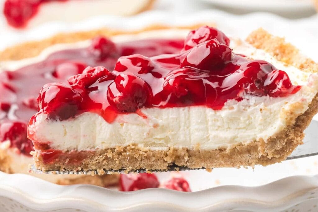 Slice of cherry cream cheese pie being lifted from a white plate.