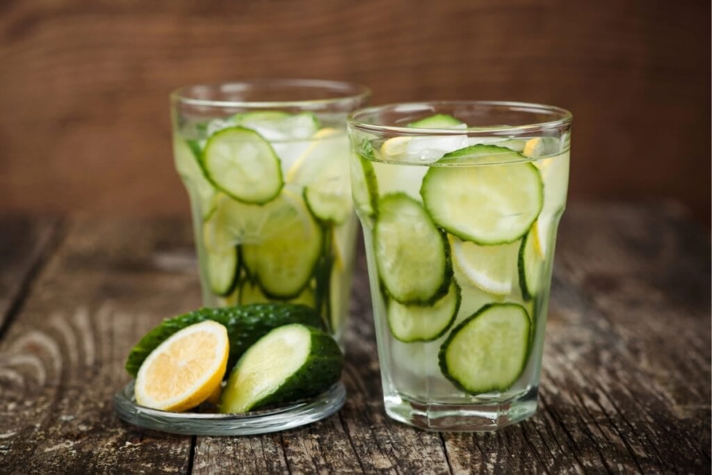 Two glasses of water with cucumber and lemon slices.