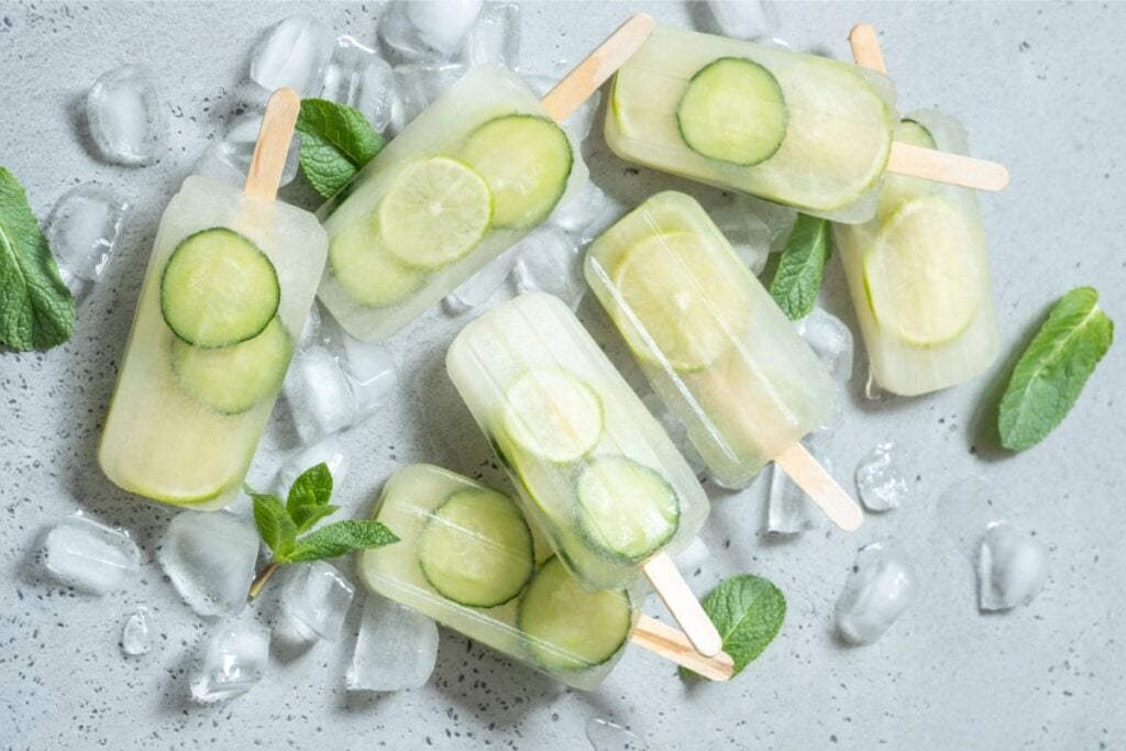 Cucumber popsicles on background with ice and mint.