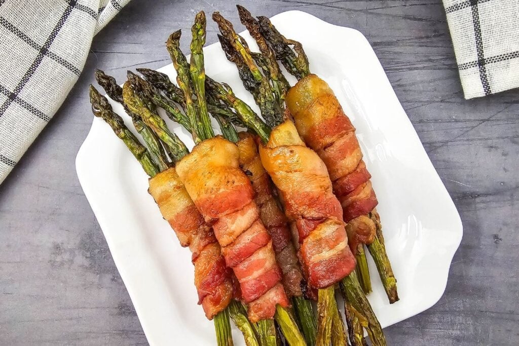 Close-up of bacon-wrapped asparagus on a table with a cloth on the side.