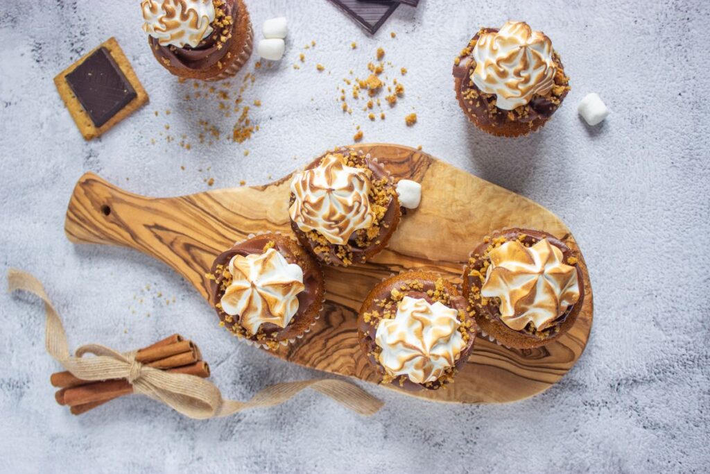 Pumpkin s’mores cupcakes with toasted frosting on a wooden board.