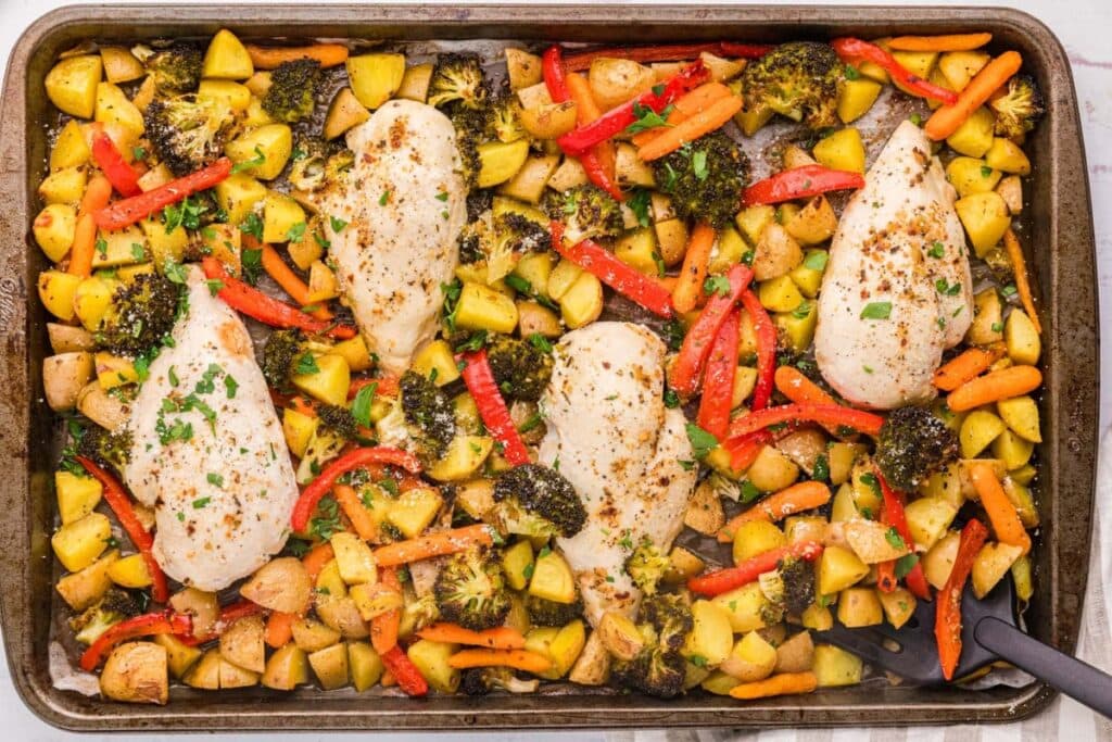 Garlic butter chicken and veggies on a baking pan.
