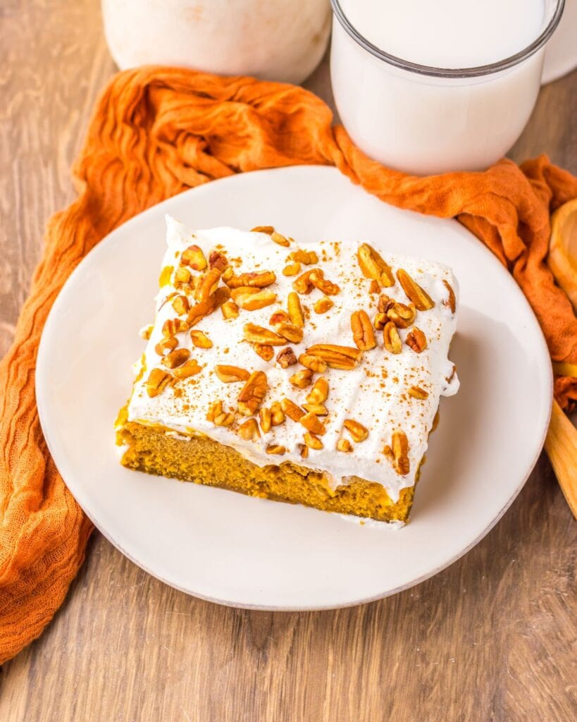 Slice of pumpkin gingerbread poke cake on a white plate.