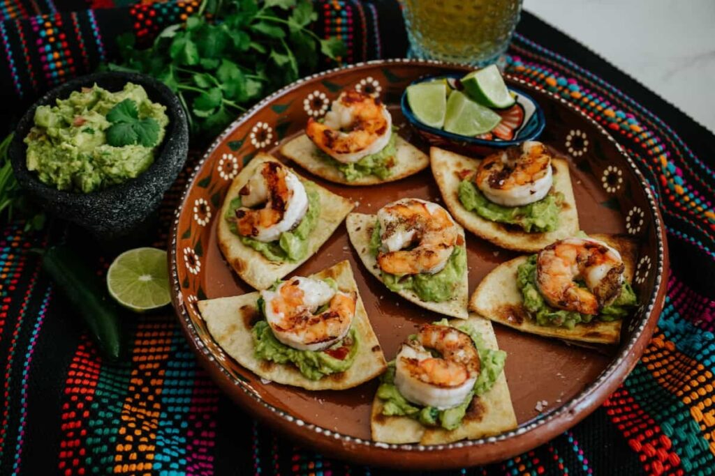 Grilled shrimp tortilla chip bites on a brown ceramic plate.