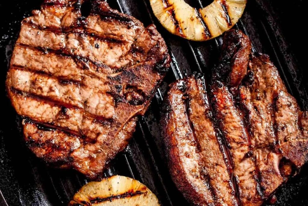 Hawaiian grilled pork chops cooking on a grill pan.