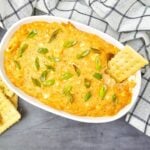 Hot crab dip served in a rectangular dish with crackers on the side.