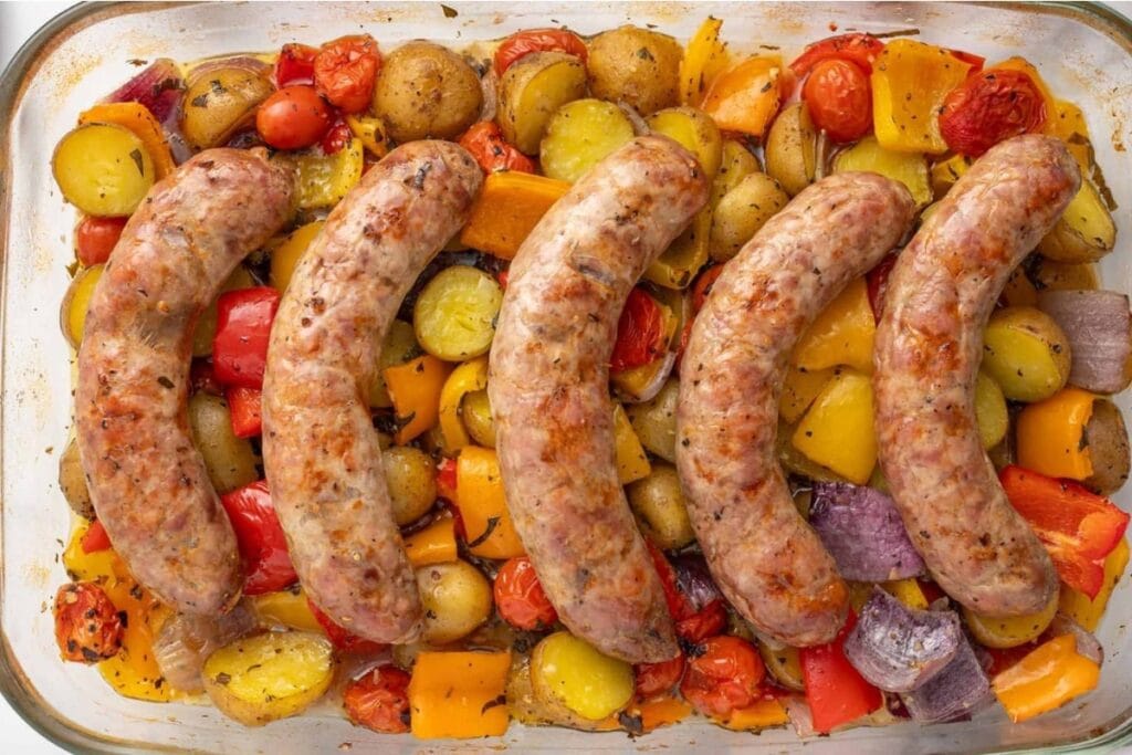 Baked Italian sausage with vegetables on a rectangular baking pan.