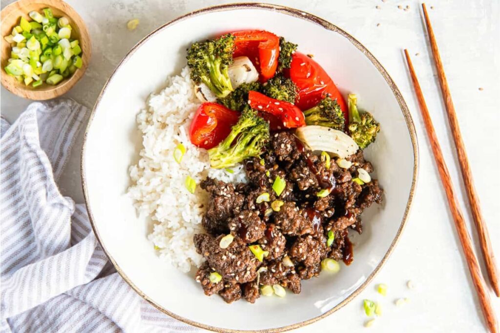 Korean ground beef with vegetables and rice served in a white bowl.