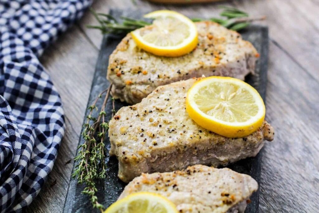Lemon pepper pork chops on a sizzling rectangular plate.