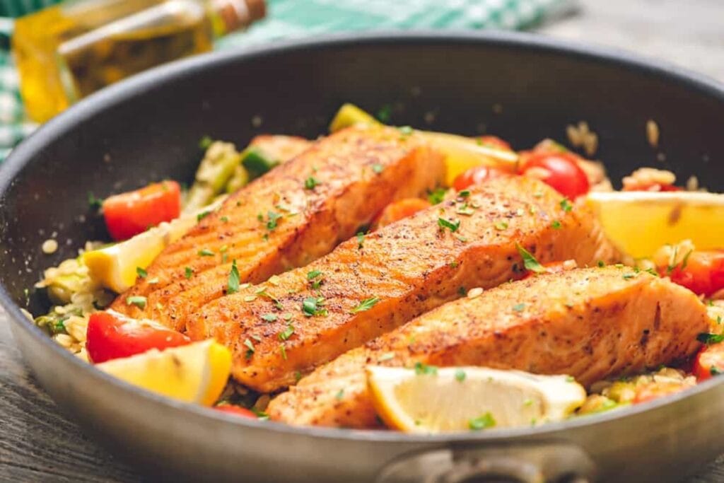 Lemon salmon with orzo pasta in a skillet.