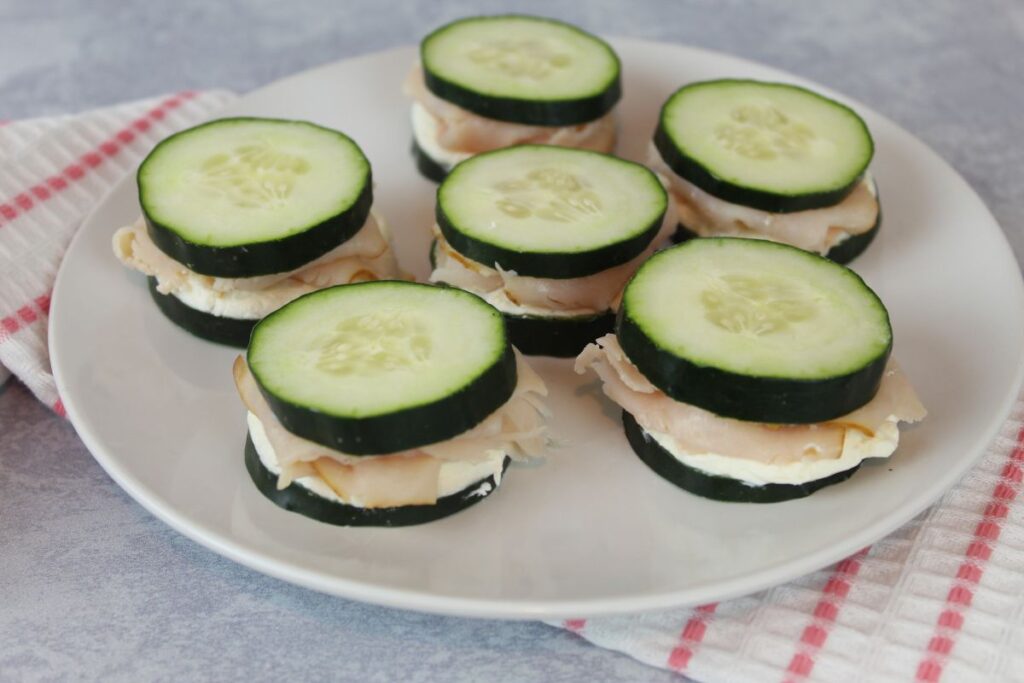 Mini cucumber sandwiches on white plate.