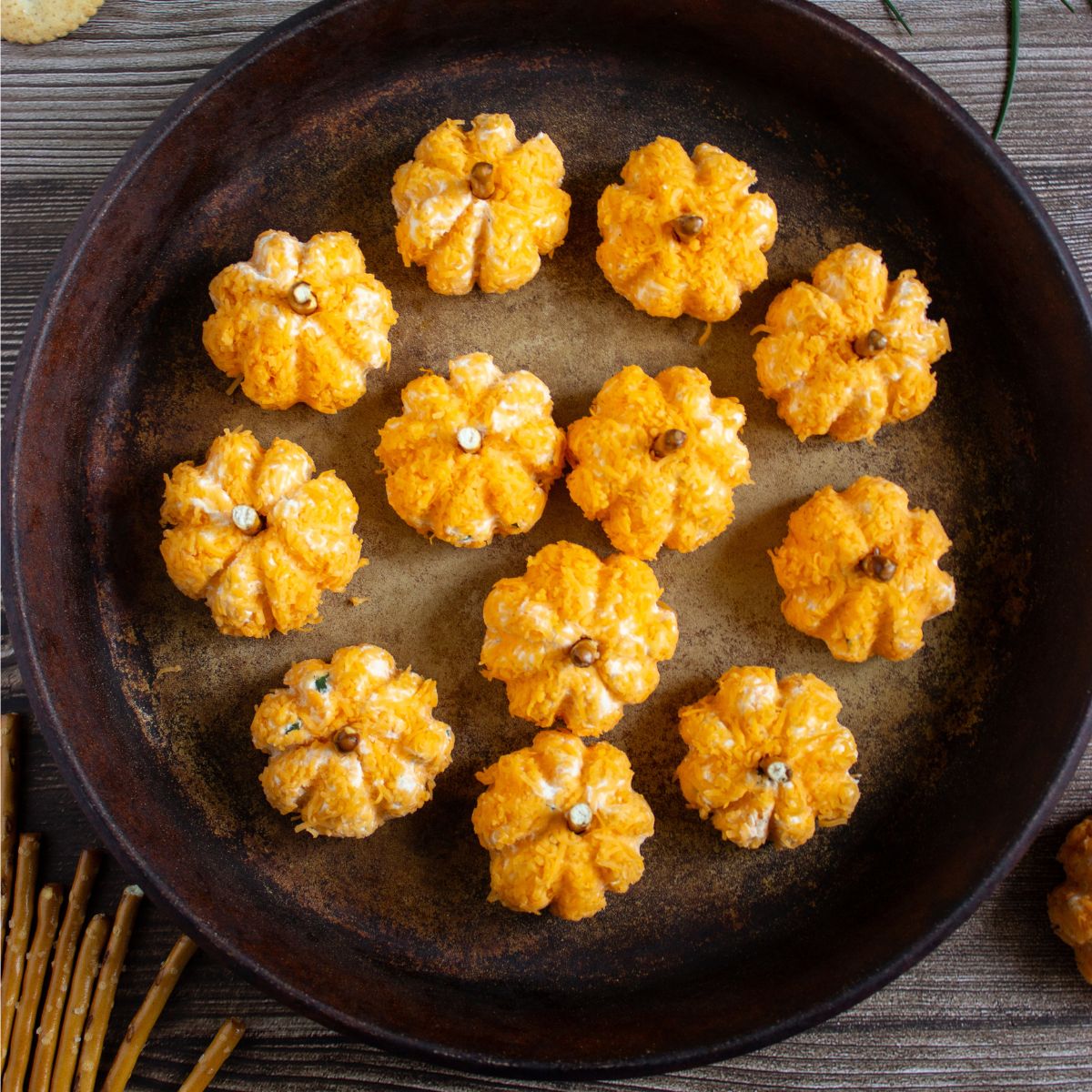 Top view of mini pumpkin-shaped cheese balls on a rustic tray.
