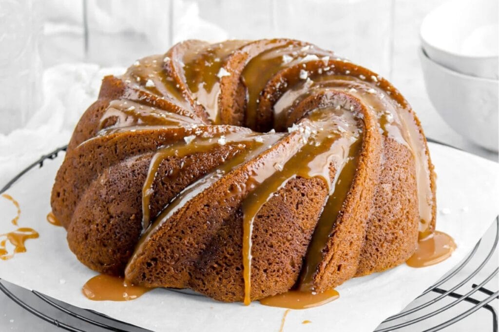 Mocha swirled Bundt cake with salted caramel sauce on a cooling rack.