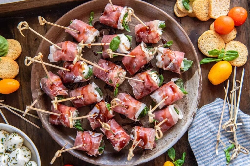 Prosciutto wrapped mozzarella bites on a rustic plate.