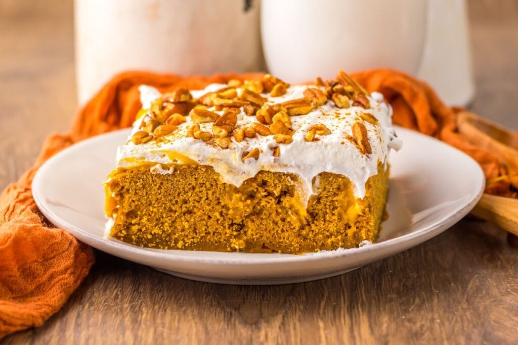 Slice of pumpkin gingerbread poke cake on a white plate.