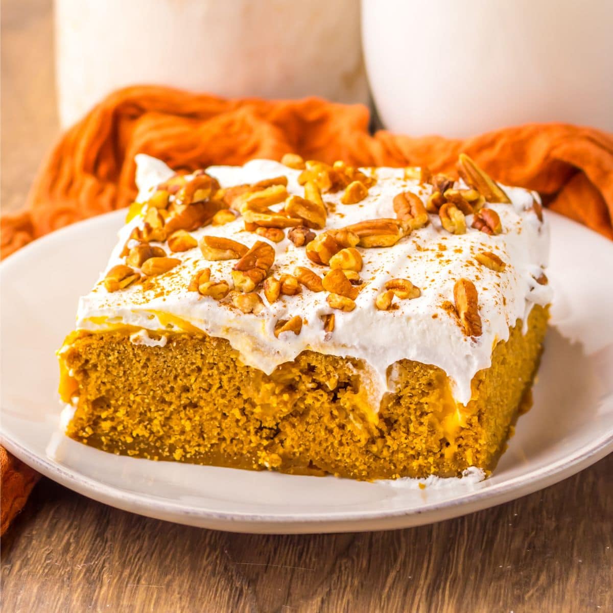 Slice of pumpkin gingerbread poke cake on a white plate.