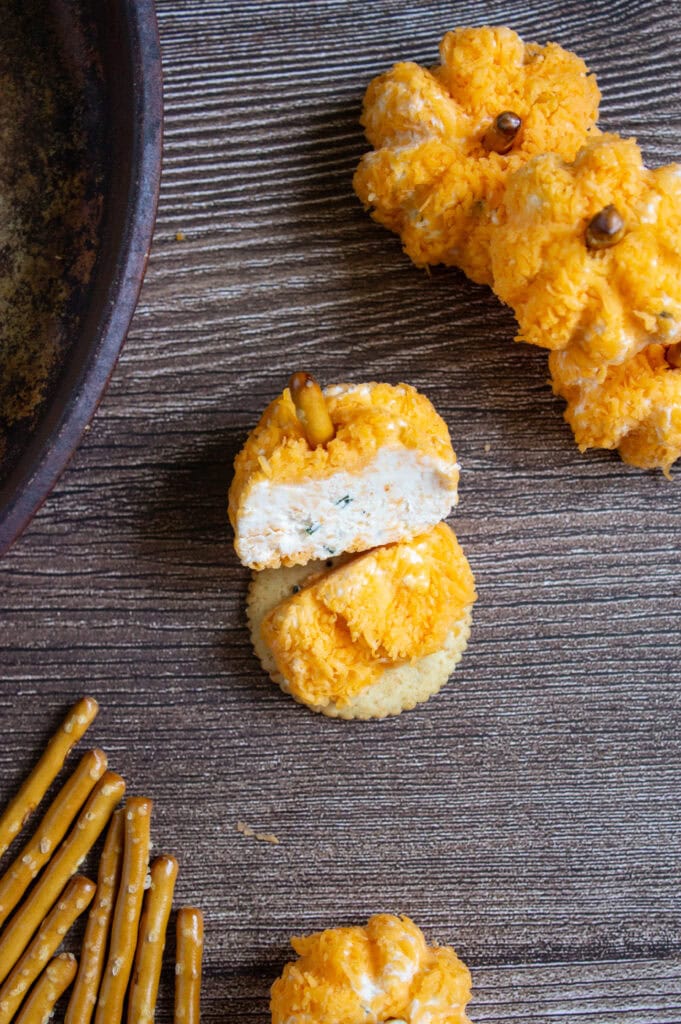 Sliced pumpkin-shaped cheeseball on a gray wooden table.