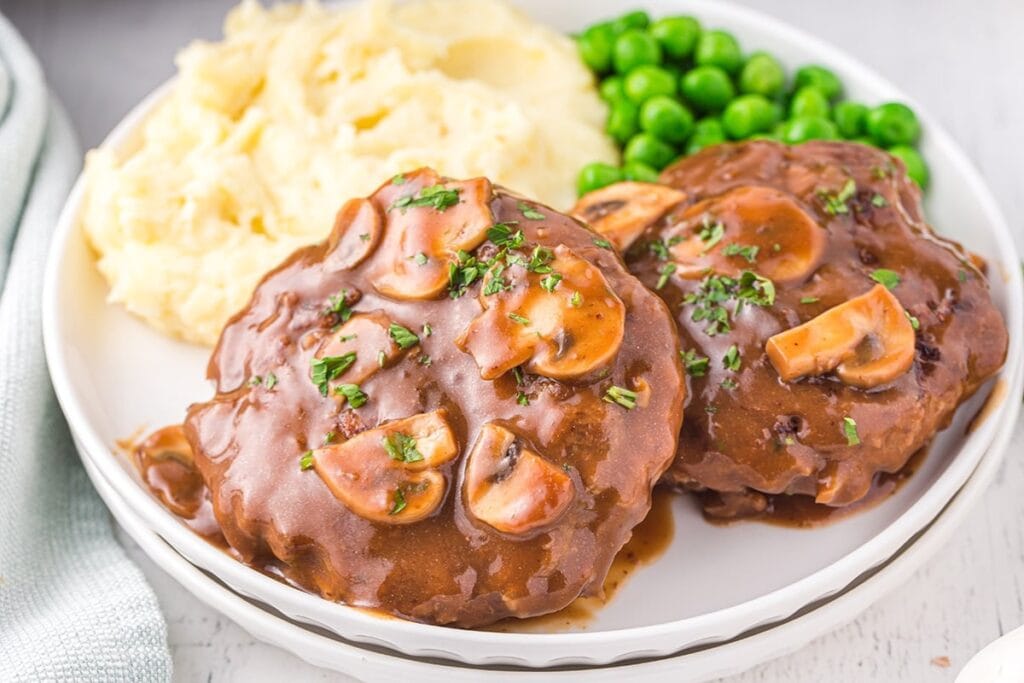 Salisbury steak served with rice on a white plate.