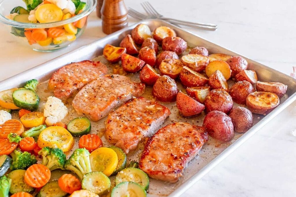 Honey garlic pork chops and vegetables on a sheet pan.