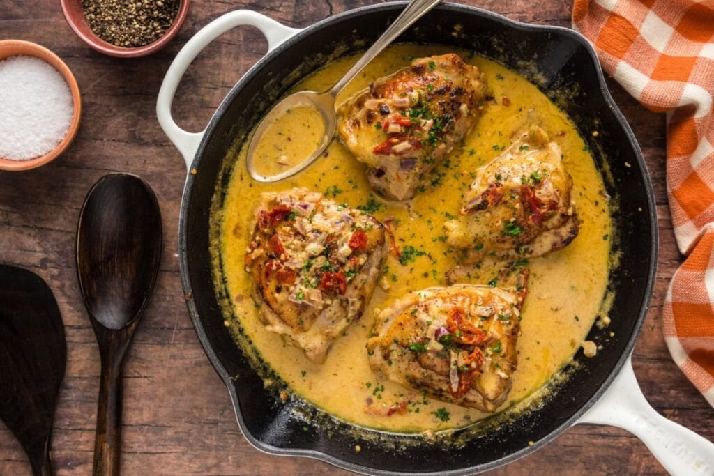 Creamy chicken thighs with spices in a skillet.
