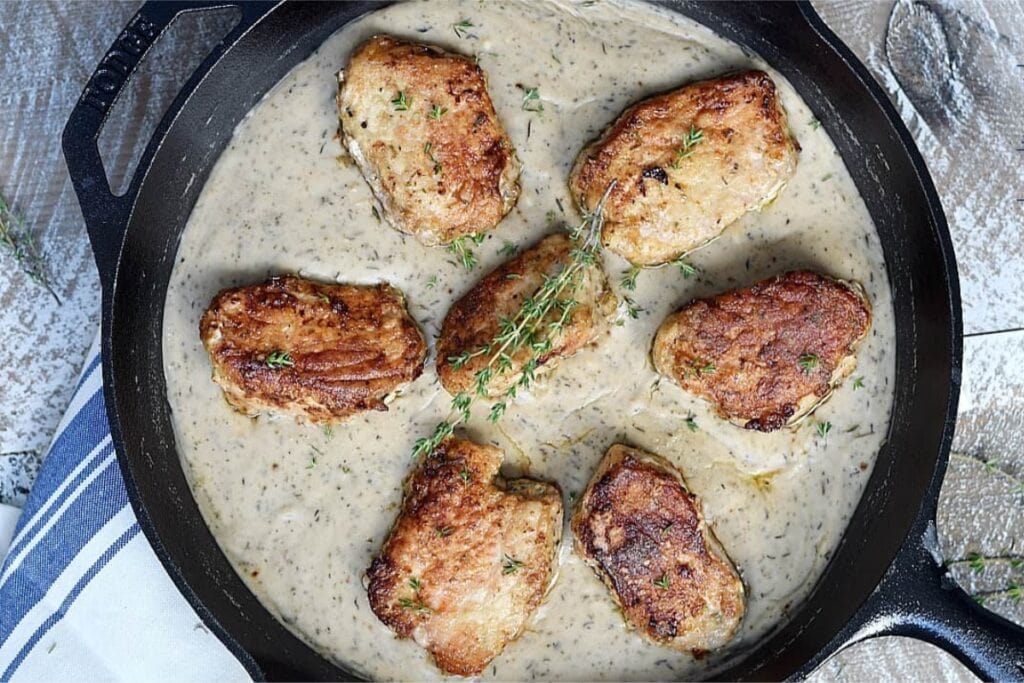 Pork chops in a skillet, with creamy herb gravy.