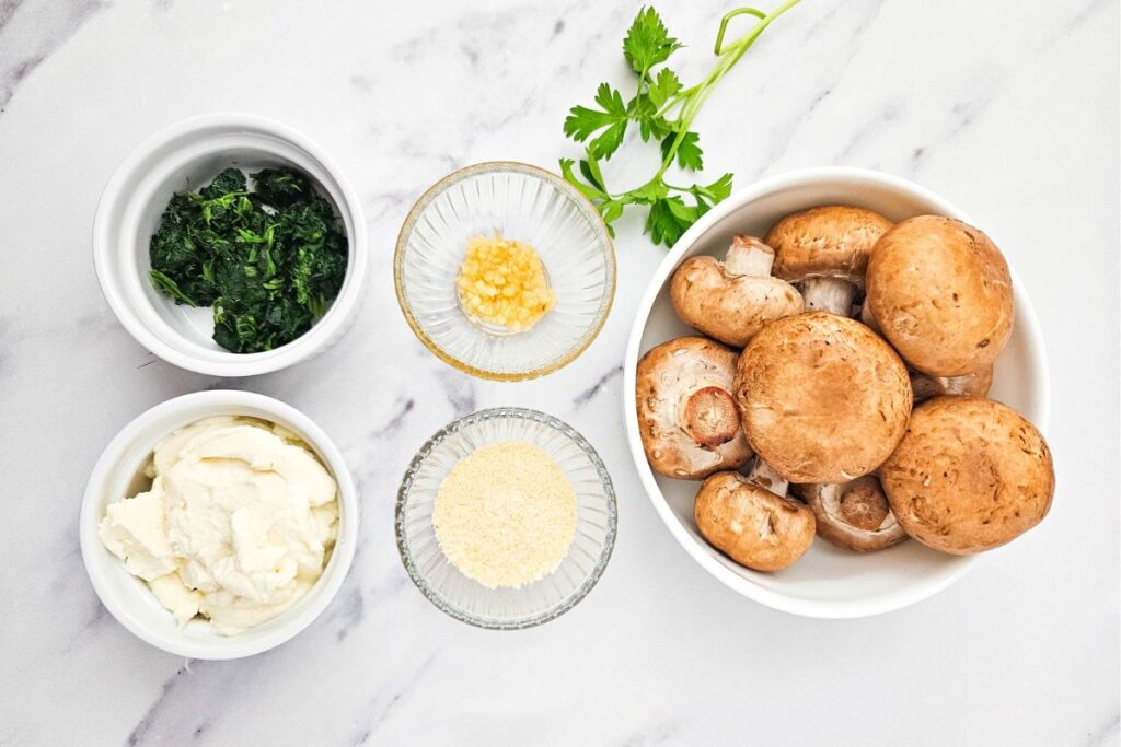 Spinach stuffed mushrooms ingredients on a marble table.