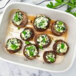 Stuffed mushrooms on a white rectangular baking dish.