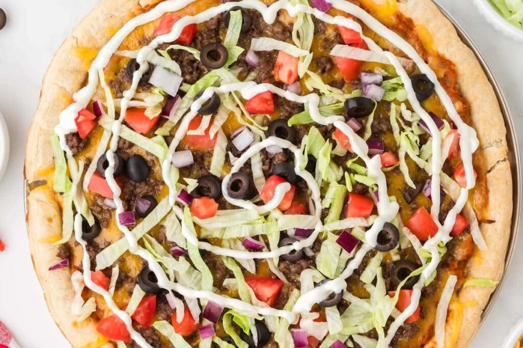 Taco pizza on a round flat baking pan.
