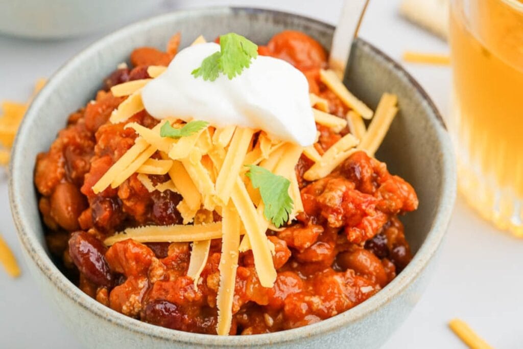 Turkey chili in a bowl, topped with shredded cheese and Greek yogurt.