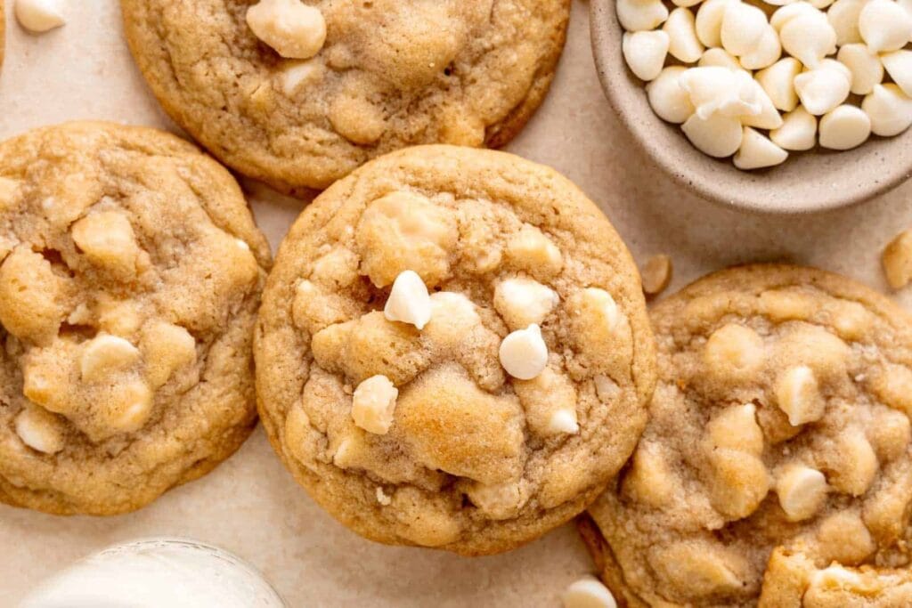 White chocolate macadamia nut cookies beside a mini bowl of white chocolate chips.